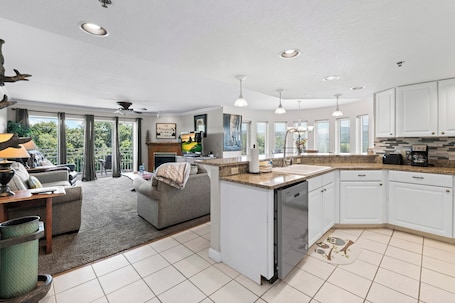A spacious kitchen with white cabinets, a dishwasher, and a large island.