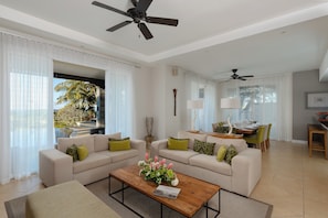 A modern living room with two sofas, a coffee table with flowers, and a dining area with a table and chairs.