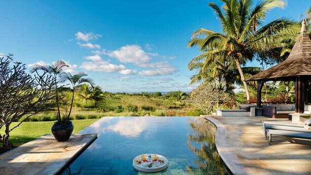 Una piscina con vista a un paisaje exuberante, un pabellón y mobiliario de exterior.