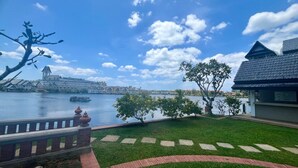 A waterfront view with a grassy lawn, a brick pathway, and a building with a tiled roof. - Luxurious Laguna Phuket Large 2-bedrooms 2 Bathrooms Ensuite With Large Pool (Choeng Thale)