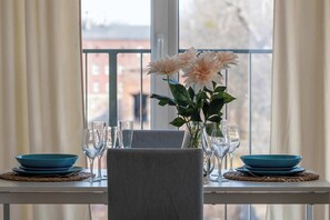 A dining table set with blue plates, clear glasses, and a vase with flowers. - Bright Apartment in Lodz | Parking, Balcony, Close to Museum (Łódź)