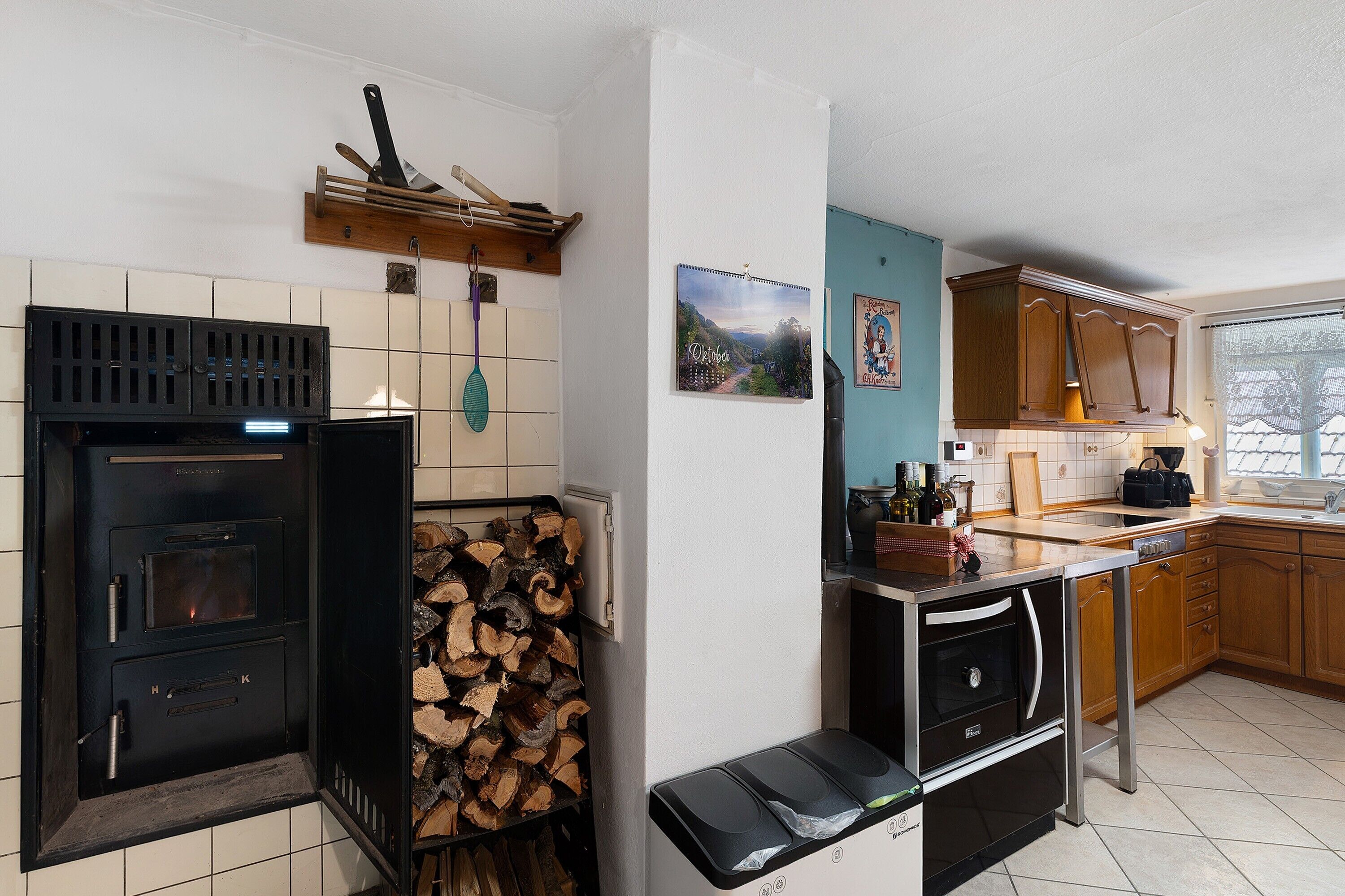 A kitchen with a wood stove, a sink, cabinets, and a window.
