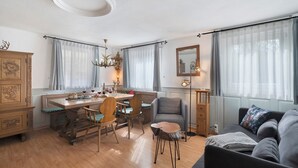 Una sala moderna con comedor, muebles de madera y una araña.