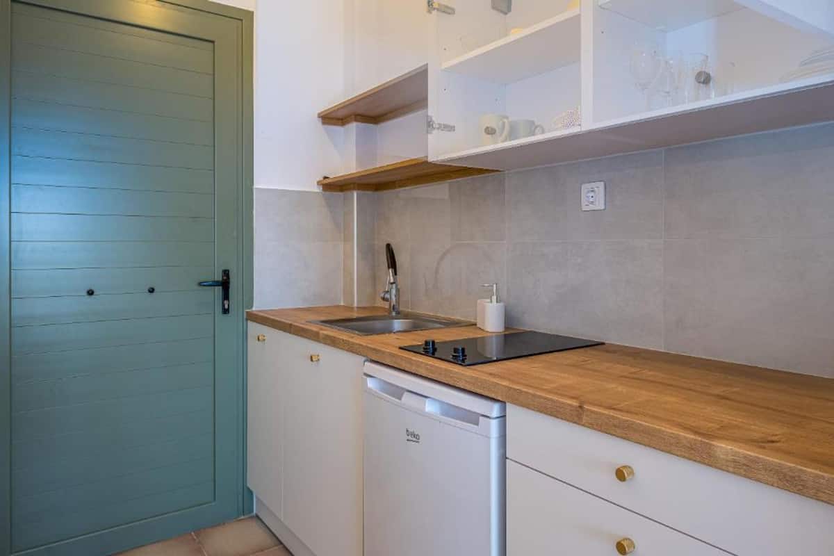 Eine Küche mit einer Holzausziehtafel, einem Geschirrspüler und einer grünen Tür.