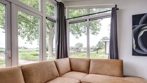 Ein Ecksofa mit Blick auf eine grüne Landschaft durch große Fenster.