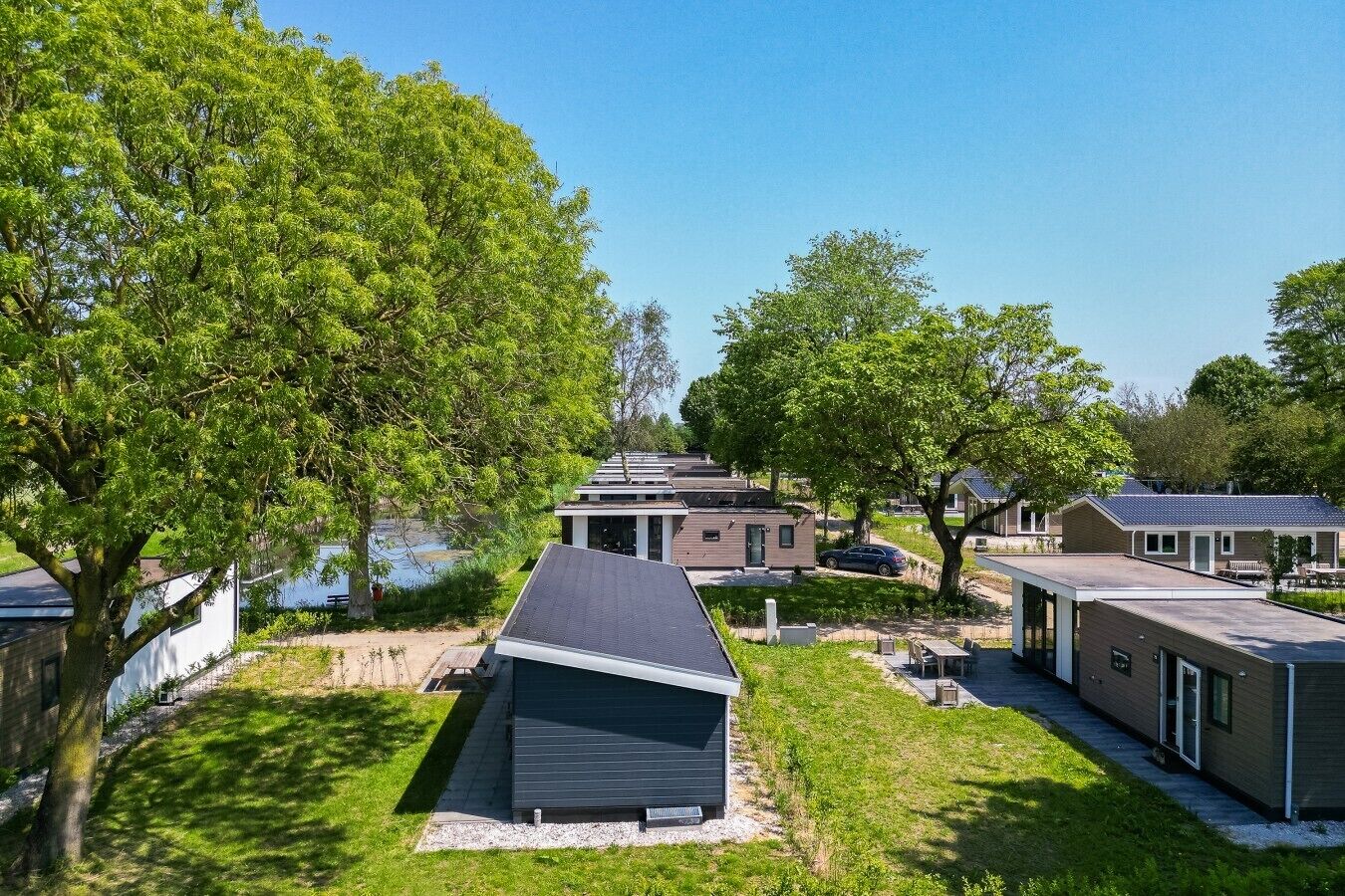 Uma fileira de casas móveis modernas, com uma área gramada e árvores ao primeiro plano.