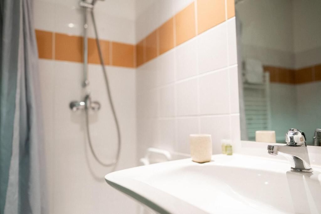 Un baño con ducha, lavamanos y espejo.
