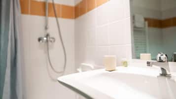 Un baño con ducha, lavamanos y espejo.