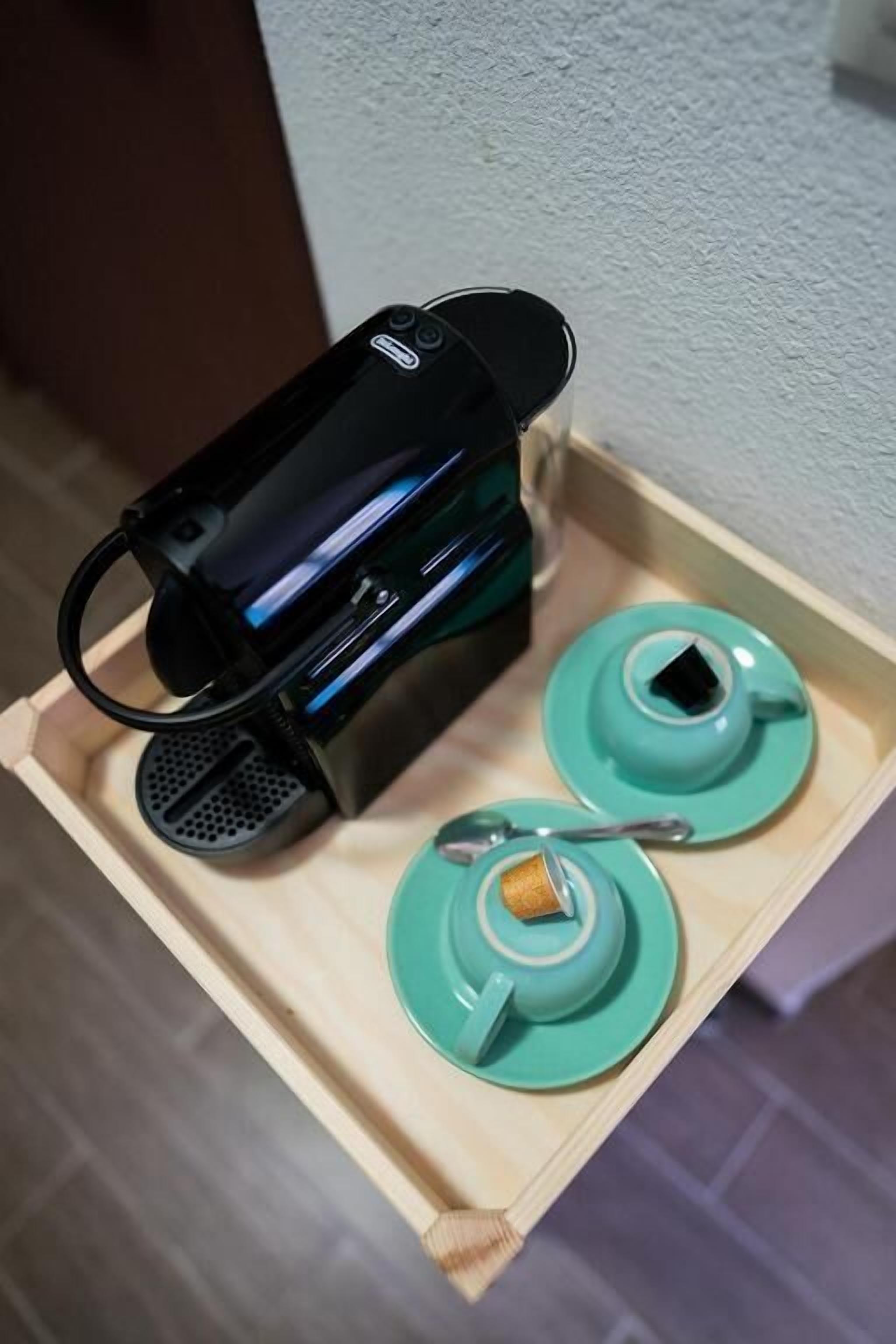 A small black device on a wooden tray with two teal plates and a spoon.