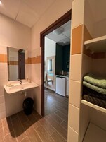 Casa de banho com lavatório, espelho e um contentor de lixo.