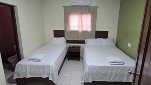 Une chambre d’hôtel avec deux lits, une table de chevet, une porte de salle de bain et un appareil de climatisation.