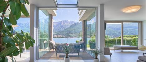 A modern living room with a large glass door leading to a balcony with a mountain view.