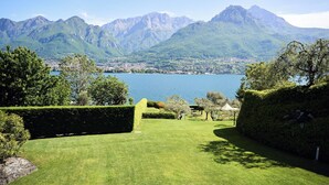 A well-maintained lawn with neatly trimmed hedges, a clear view of a lake, and mountains in the background. - Villa Costanza (Oliveto Lario)