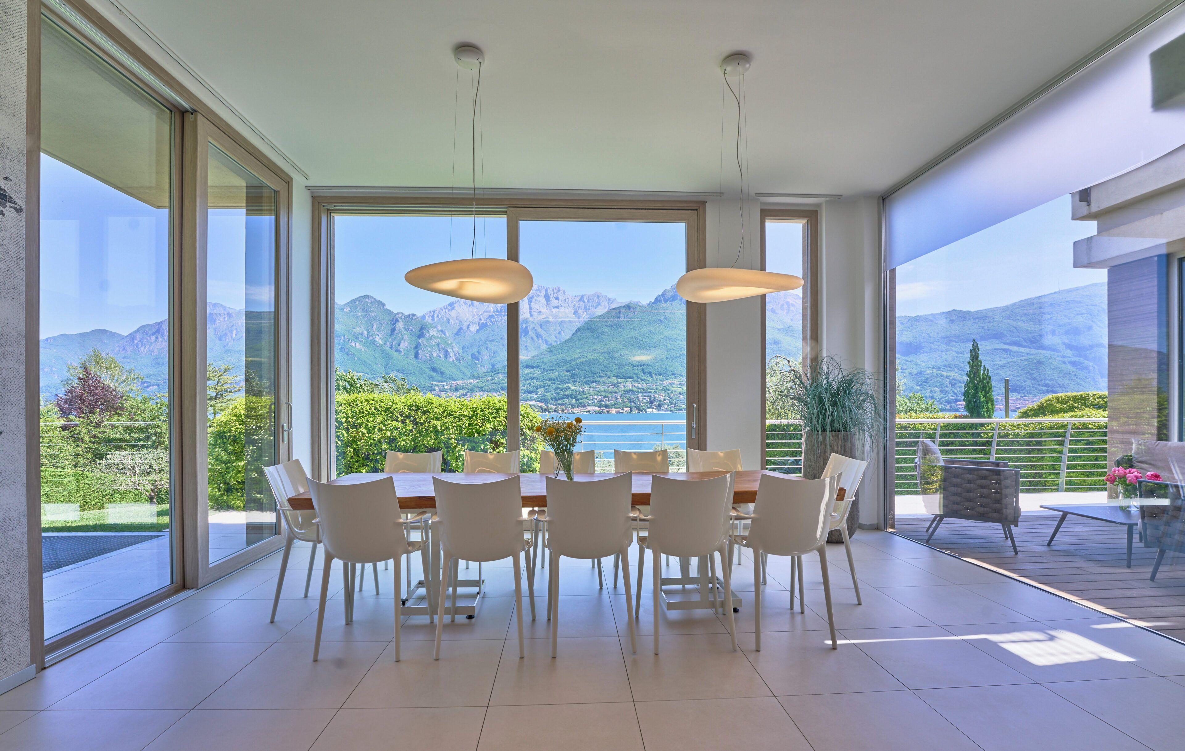 Un comedor con mesa y sillas, ventanas amplias con vista a la montaña e iluminación colgante.