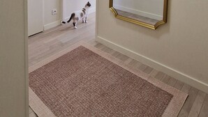 A hallway with a large mirror, a door, and a cat.