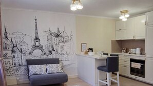 A compact room with a bed, a sofa, a desk, and a kitchenette.