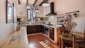 A kitchen with wooden cabinets, a central island, a stove, and a hanging light fixture.