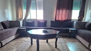 A living room with a sofa set, a coffee table, and a patterned rug. - Luxurious 3-bedroom Apartment in Historic Fès, Morocco (Fes)