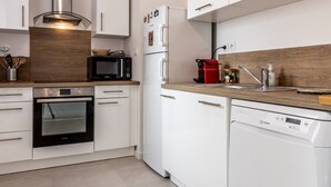Una cocina moderna con armarios blancos, electrodomésticos de acero inoxidable y encimera de madera.