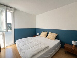 Ein Schlafzimmer mit einem Bett, zwei Nachttischen, einem Fenster und Blick ins Freie.