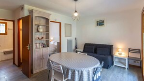 A cozy living room with a round table, a sofa, a bookshelf, and a hanging light fixture. - Chalet with terrace - 5 guests quiet Cauterets (Cauterets)