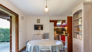 A compact kitchen with a dining area, a TV mounted on the wall, and a bookshelf. - Chalet with terrace - 5 guests quiet Cauterets (Cauterets)