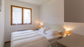 A bedroom with two beds, a window with curtains, a bedside lamp, and a ceiling light. - Chalet with terrace - 5 guests quiet Cauterets (Cauterets)