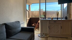 Una sala de estar con un sofá, un aparador, una mesita y un ventanal con vistas.