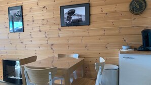 Una habitación con paneles de madera, una mesa y sillas, una cafetera y cuadros en la pared.