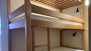 Una cama litera con estructura de madera y ropa de cama blanca.