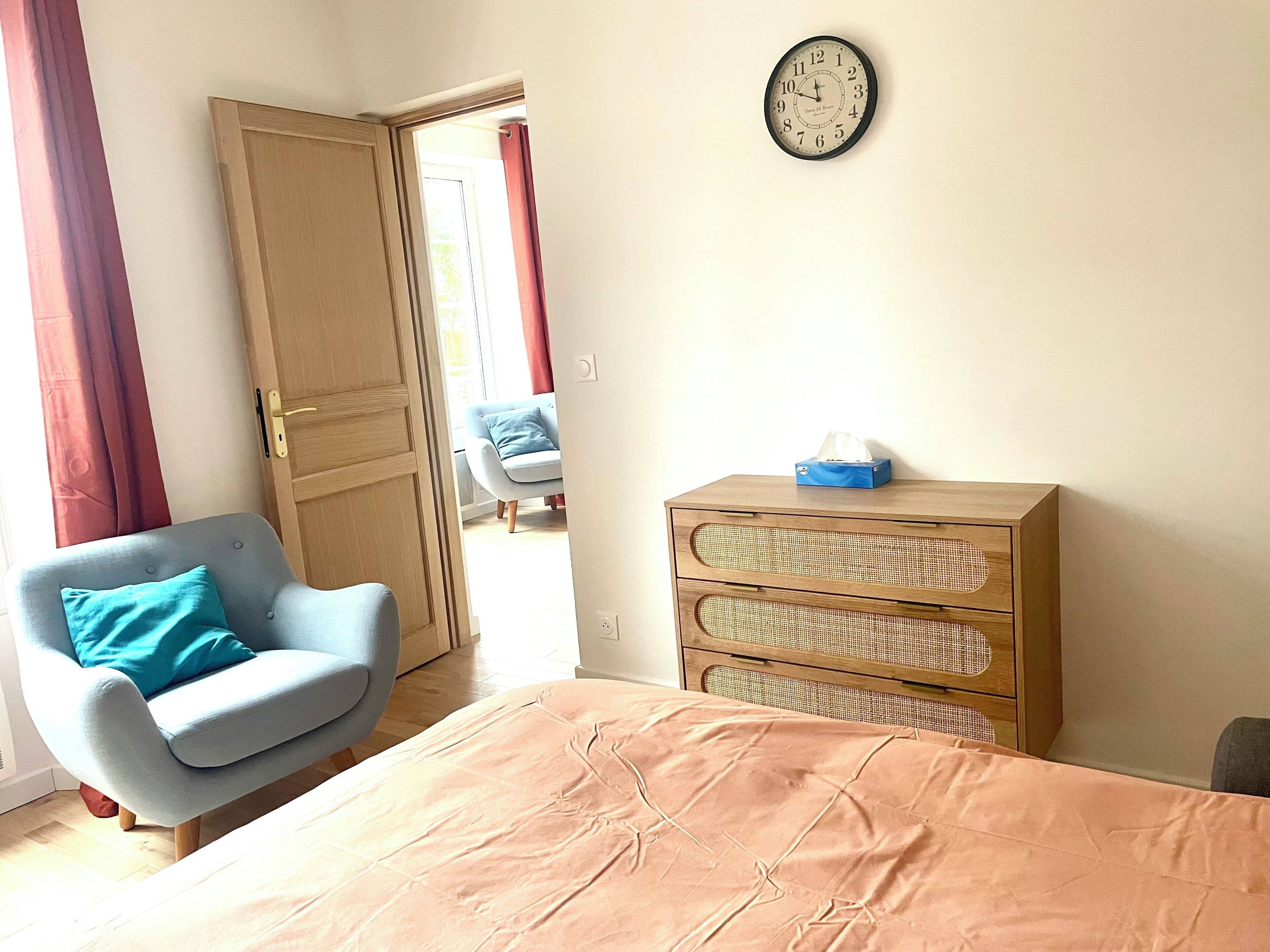 Een kamer met een bed, een stoel, een kaptafel en een wandklok.