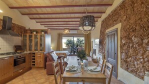 A kitchen with wooden cabinets, a stove, and a dining area with a table set for two.