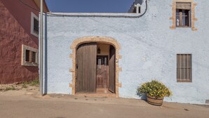 A building with a large arched doorway, a small window, and a potted plant.