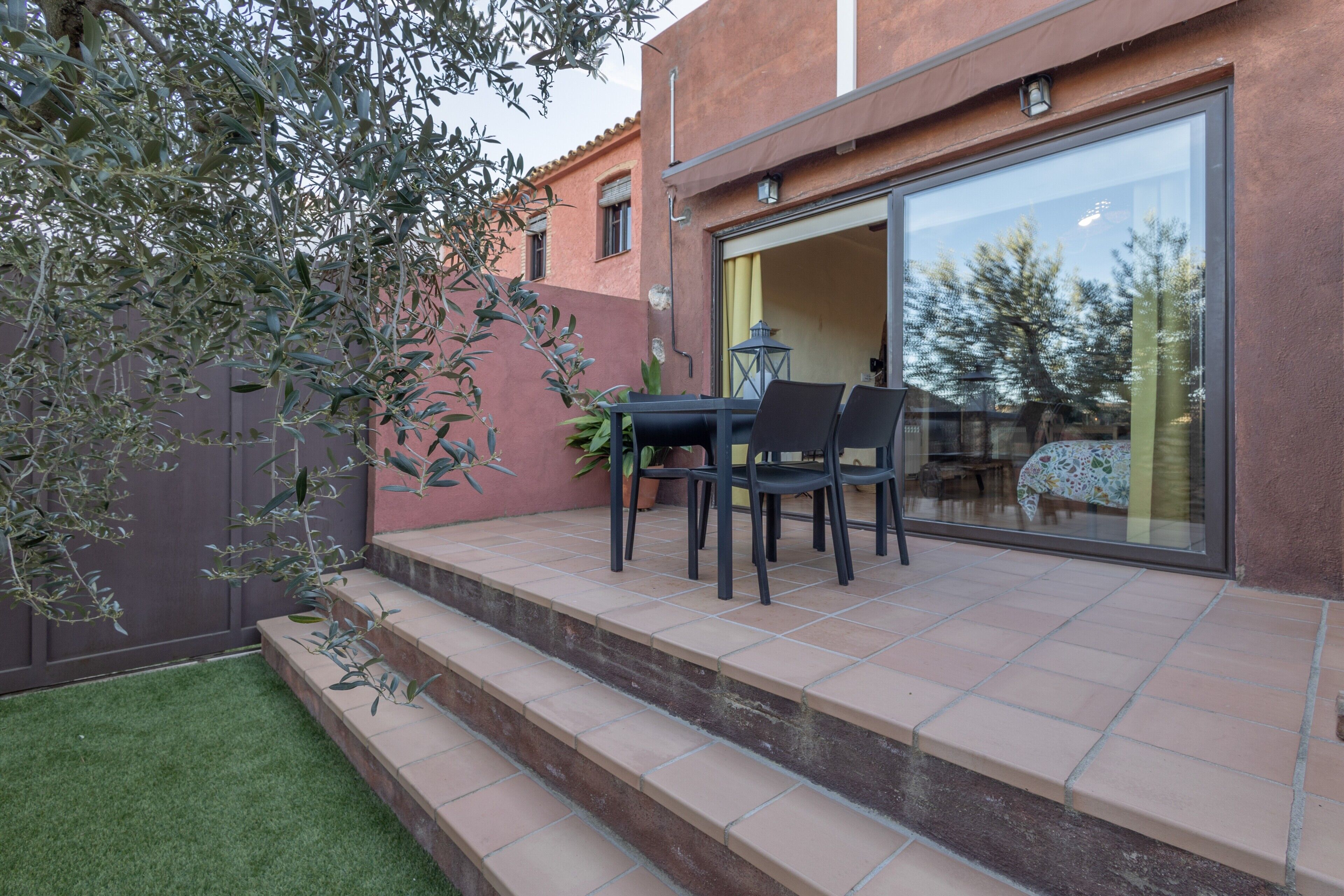 A patio with a table and chairs, a glass door leading to an interior space, and a small step leading to the patio.