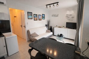 Ein kompakter Wohnbereich mit Küchenzeile, Essbereich, einer Couch und einem Fernseher.
