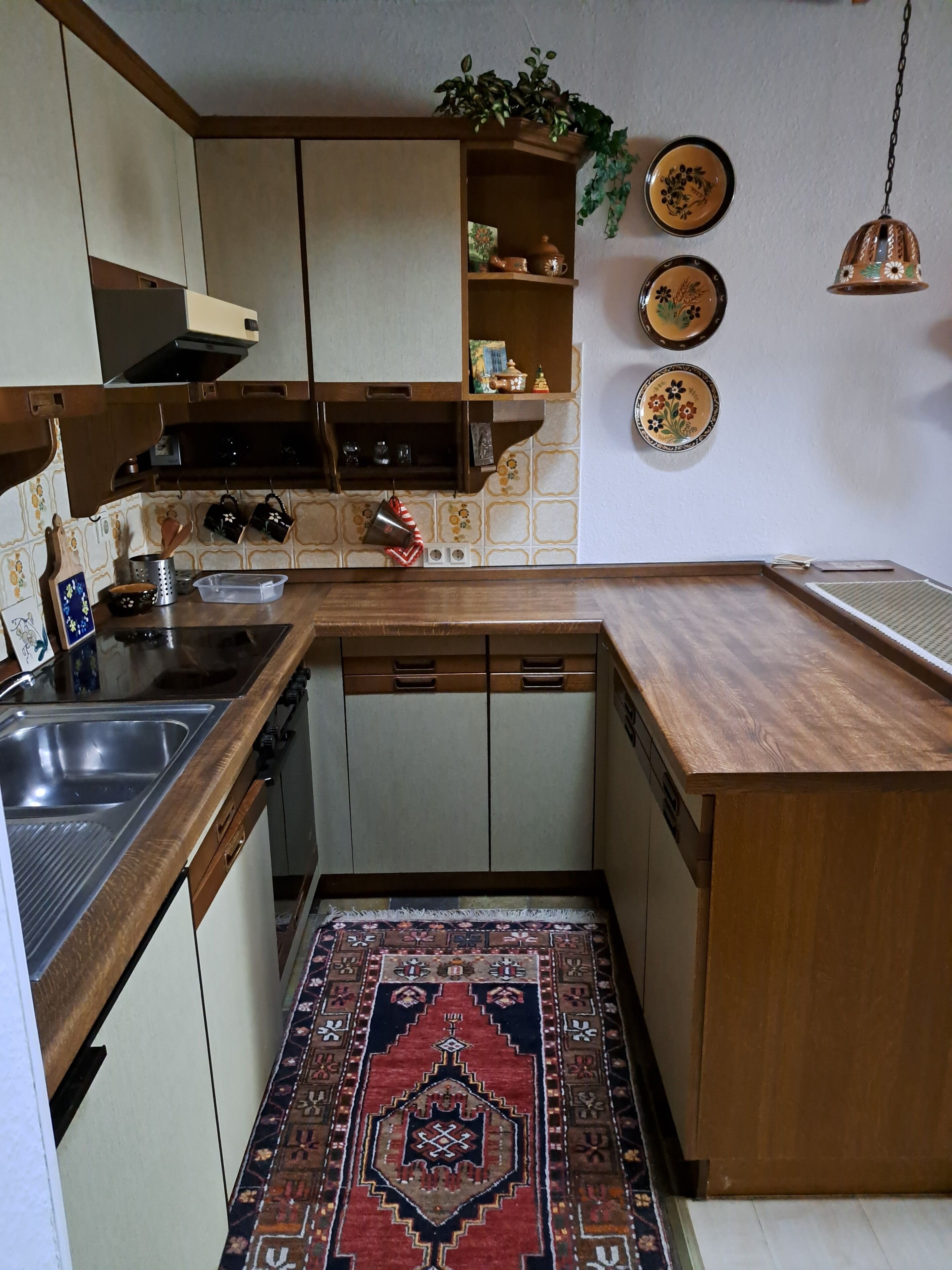 Una cucina con piano di lavoro in legno, lavello in acciaio inossidabile e tappeto decorato.