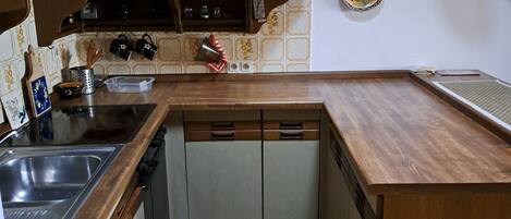 Una cucina con piano di lavoro in legno, lavello in acciaio inossidabile e tappeto decorato.