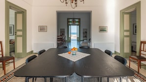 A dining area with a long table, chairs, a chandelier, and a view through a doorway. - Exclusive beachfront villa, 6 bedrooms, garden, Monopoli (Monopoli)