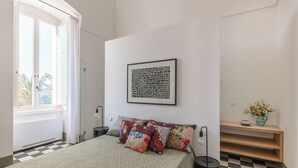 A bedroom with a checkered floor, a bed with patterned bedding, a framed artwork on the wall, and a small shelf with a vase. - Exclusive beachfront villa, 6 bedrooms, garden, Monopoli (Monopoli)