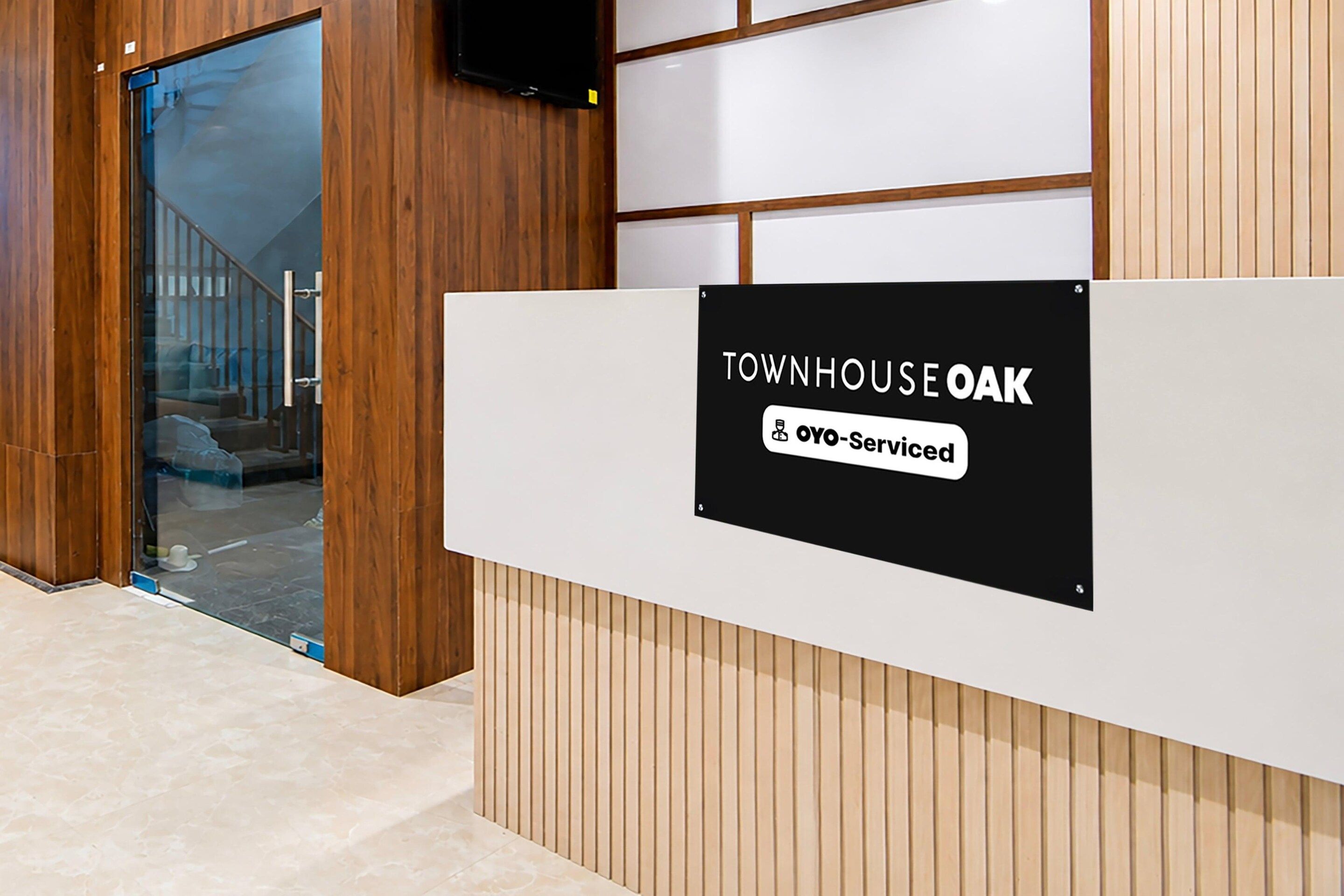 Een receptiebalie met een bord waarop 'TOWNHOUSE OAK' en 'Oyo-Serviced' staat.