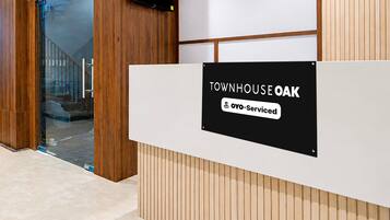 Een receptiebalie met een bord waarop 'TOWNHOUSE OAK' en 'Oyo-Serviced' staat.