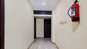 A hallway with a fire extinguisher mounted on the wall, a door at the end, and a light switch. - Townhouse OAK Howrah Oak Belilious Park (Howrah)