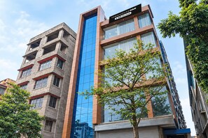A modern building with a prominent blue glass facade and a sign indicating it is serviced by OYO. - Townhouse OAK Howrah Oak Belilious Park (Howrah)