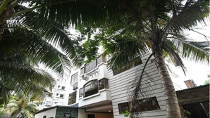 A modern hotel with a white facade, multiple balconies, and a palm tree in the foreground. - Townhouse OAK Howrah Oak Belilious Park (Howrah)