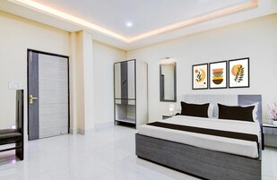 A modern bedroom with a large bed, a wardrobe, a bench, and a mirror.