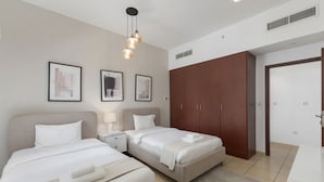 A hotel room with two beds, a wardrobe, and framed pictures on the wall. - Cozy JBR 2BR Retreat Steps to the Beach The Walk (Dubai)