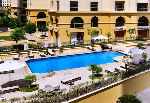 A hotel with a large pool, outdoor seating, and a restaurant. - Cozy JBR 2BR Retreat Steps to the Beach The Walk (Dubai)