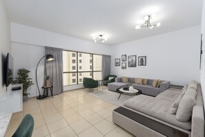 A modern living room with a sofa, armchair, and a flat-screen TV. - Cozy JBR 2BR Retreat Steps to the Beach The Walk (Dubai)