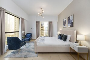 A modern hotel room with a large bed, a desk, a chair, and a view of the city. - Cozy JBR 2BR Retreat Steps to the Beach The Walk (Dubai)