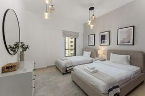 A modern bedroom with two beds, a large mirror, and pendant lighting. - Cozy JBR 2BR Retreat Steps to the Beach The Walk (Dubai)